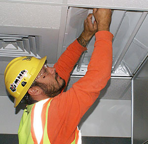 A man replace a light in commercial place
