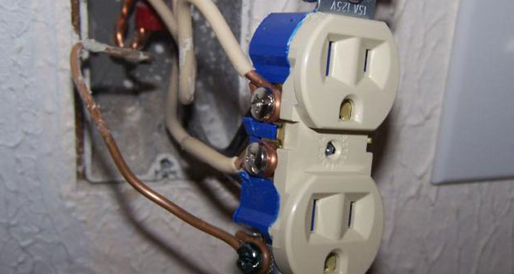 an electricians hands pull wire through outlet holes cut in new sheetrock