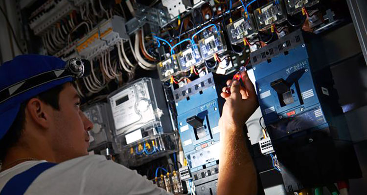 an electrician looking at breakers with a flashlight